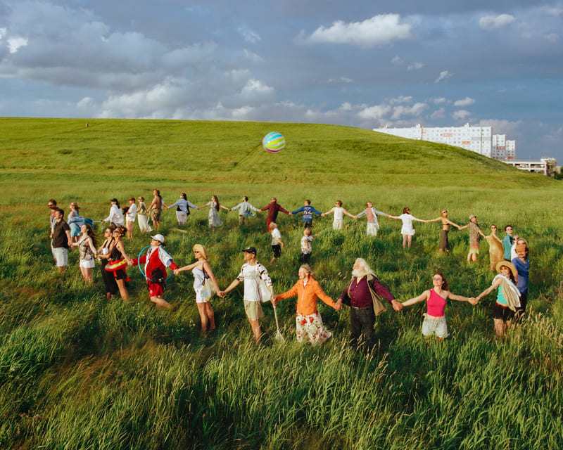 The Circle of Gratitude — A quiet circle of bodies on grass, staged in the tradition of collective ritual photography.